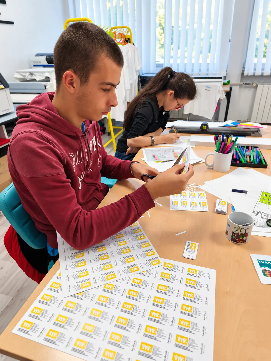 Učenik reže papir makazama tokom završne obrade školskih materijala